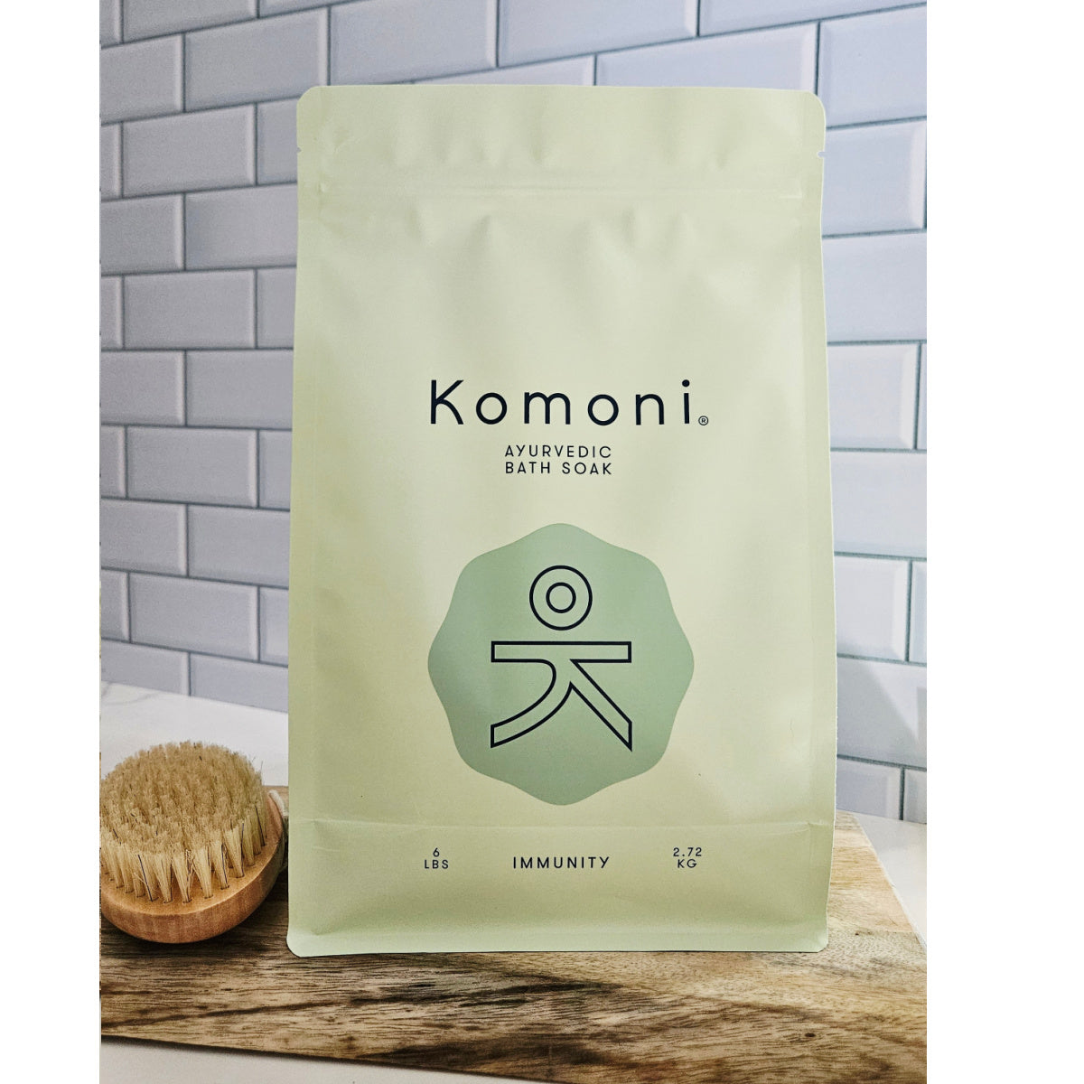 Komoni IMMUNITY Ayurvedic Bath Soak 6 pound package on a wooden surface with a tiled wall background