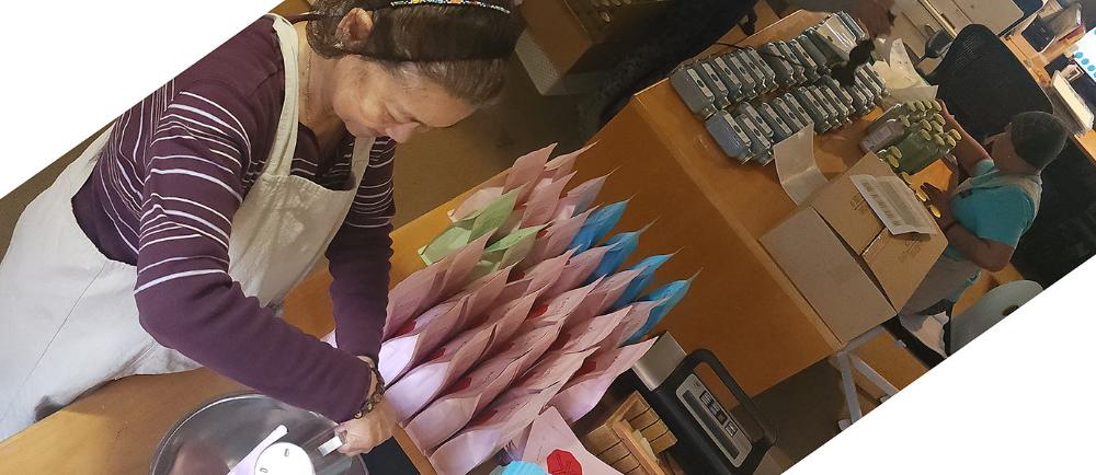 Depicts a look inside where family members heartcraft the Komoni products one by one.