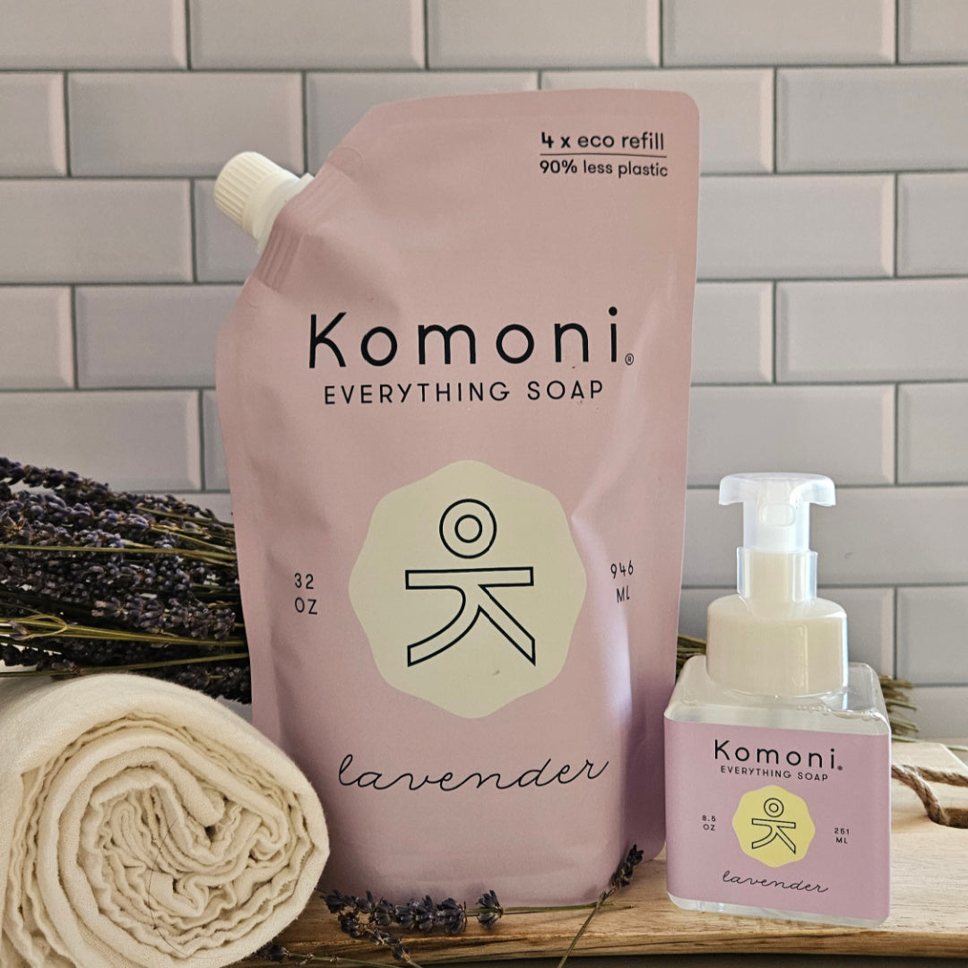 Komoni Everything Soap refill packaging with lavender scent on a wooden surface with a tiled wall background.