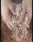 Close-up video showing the hand mixing of pink Himalayan salt crystals with pure essential oils and botanicals.