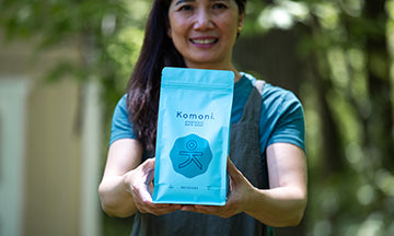 Vangie present a blue package of RECOVERY Bath Soak labeled 'Komoni' against a blurred natural background