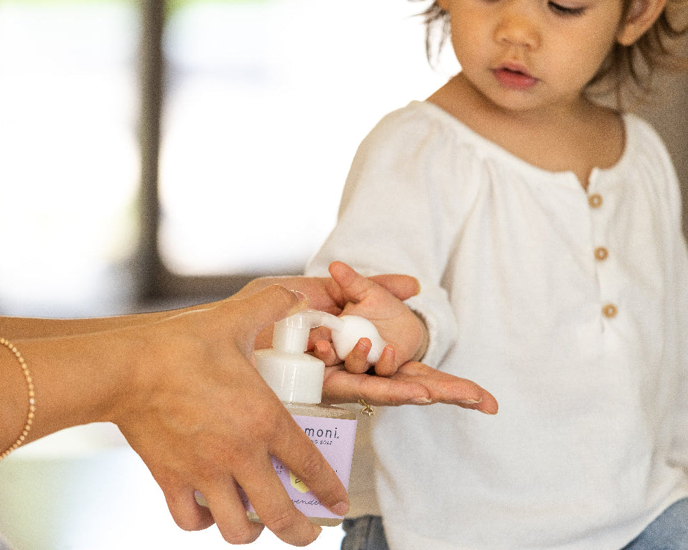Mother applying foaming botanical soap to her child's hand with a focus on the their connection.