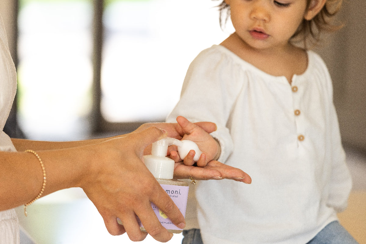 Mother applying foaming botanical soap to her child's hand with a focus on the their connection.