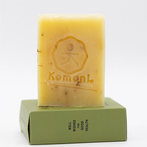 Yellow soap bar with 'Komoni' imprinted branding on a white background