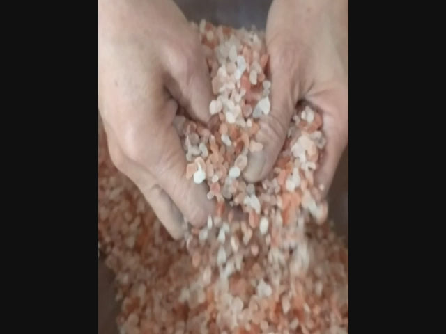 Close-up video showing the hand mixing of pink Himalayan salt crystals with pure essential oils and botanicals. 
